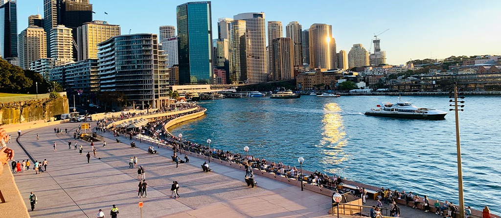 Darling Harbour at evening is filled with people walking and strolling along the foreshore.