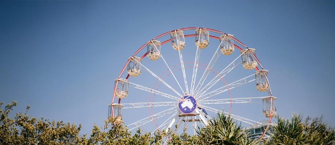 Ferris wheel at Bondi Festival in Sydney, surrounded by trees under a clear blue winter sky.
